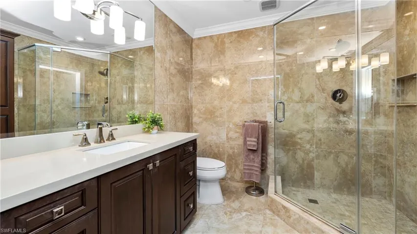Bathroom with vanity, crown molding, tile walls, and a shower stall