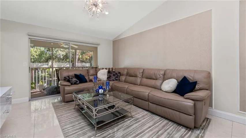 Living area featuring lofted ceiling, a chandelier, and light tile patterned flooring