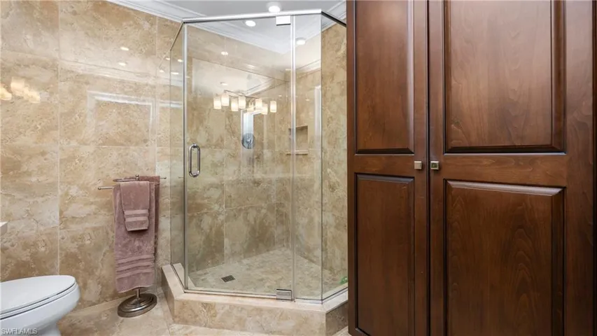 Bathroom with a shower stall, ornamental molding, and tile walls