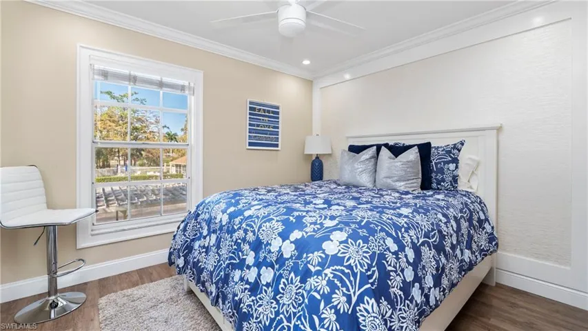 Bedroom with ornamental molding, dark wood-type flooring, and a ceiling fan