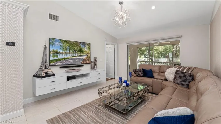 Living area featuring vaulted ceiling, light tile patterned floors, and a chandelier