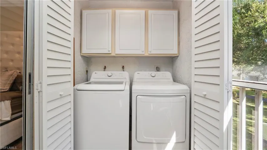 Laundry room featuring plenty of natural light, cabinet space, and washer and clothes dryer