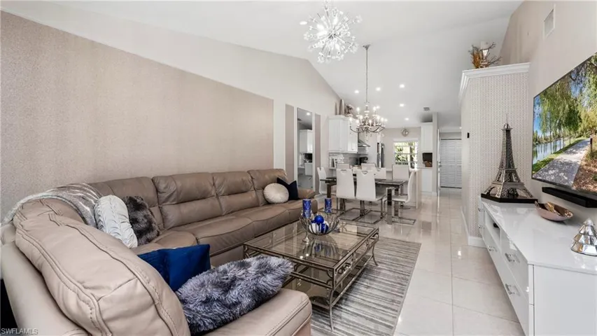 Living room featuring a chandelier, lofted ceiling, light tile patterned floors, and recessed lighting