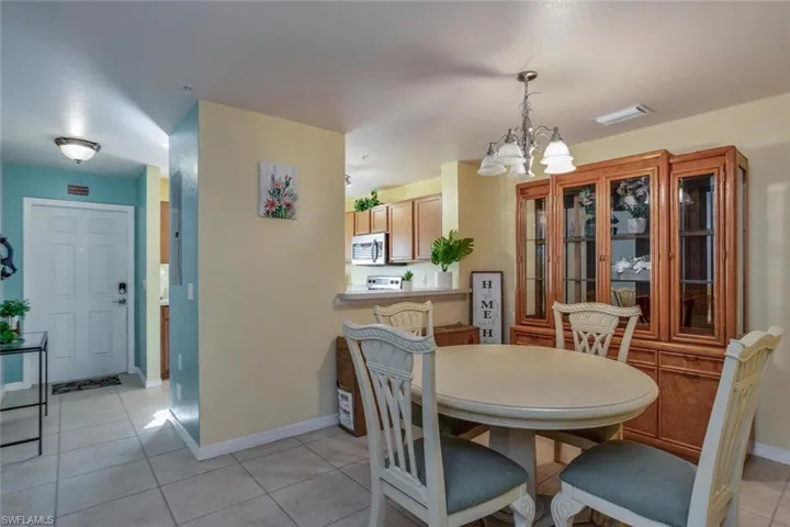 Dining room with light tile patterned flooring and an inviting chandelier
