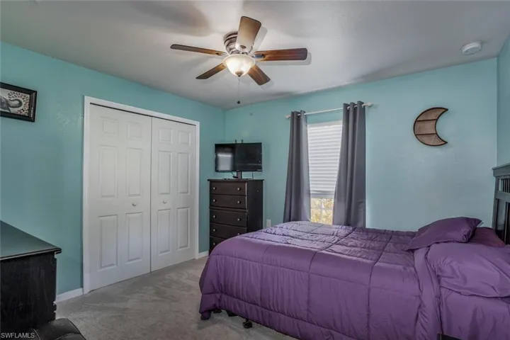 Bedroom with ceiling fan, light carpet, and a closet
