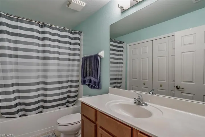 Full bathroom with a textured ceiling, vanity, toilet, and shower / bath combo with shower curtain