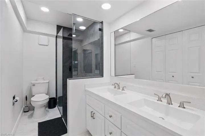 Full bathroom featuring double vanity, a stall shower, a closet, light marble finish flooring, and recessed lighting