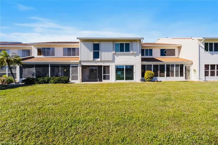 Rear view of house featuring a sunroom and a yard