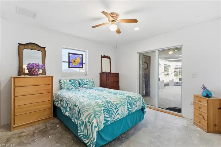 Bedroom featuring concrete flooring, access to exterior, and a ceiling fan