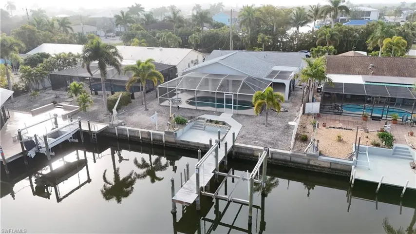 Dock featuring an outdoor pool, boat lift, glass enclosure, and a water view