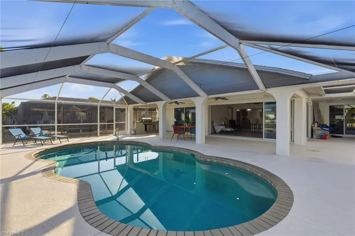 Outdoor pool with glass enclosure, a patio, and a sunroom
