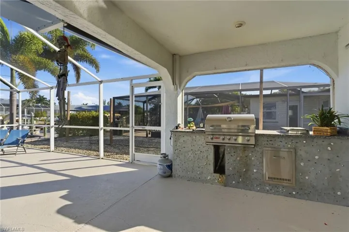 View of patio / terrace featuring a sunroom, a lanai, and exterior kitchen