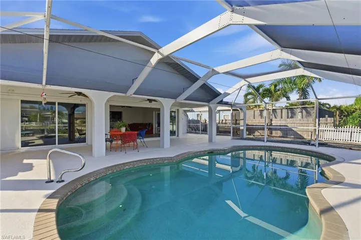 Swimming pool featuring outdoor dining space, a patio area, a sunroom, and a lanai
