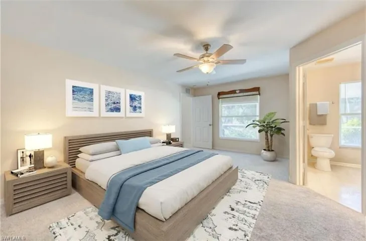 Carpeted bedroom featuring connected bathroom and a ceiling fan