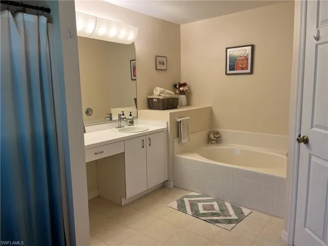 Full bath featuring vanity, a garden tub, and tile patterned floors