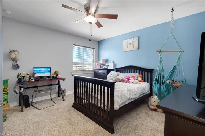 Wall-to-wall carpeting, window with blinds, ceiling fan with integrated lighting, and painted walls