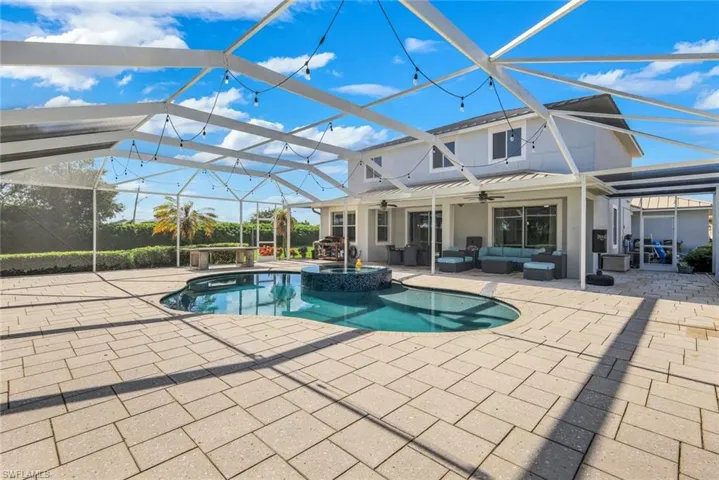 Screened-in outdoor living space with a paver patio, integrated pool, and a covered lounge area