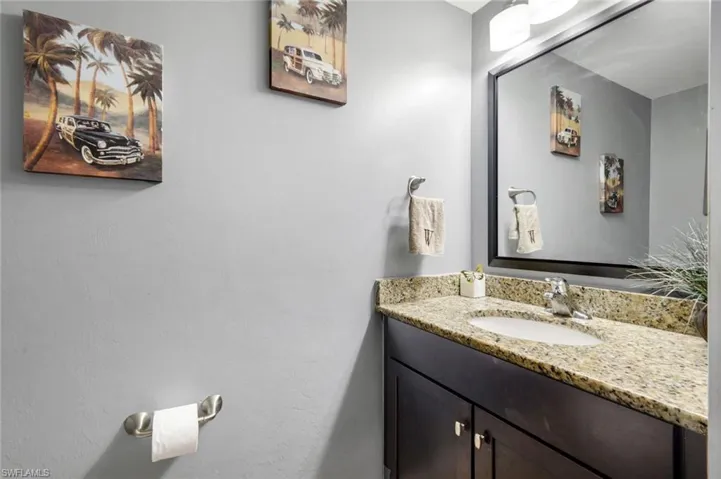 Granite countertop, undermount sink, dark wood-finish vanity, and a framed mirror