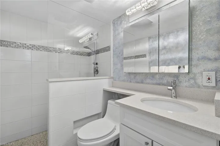 Full bath featuring walk in shower, vanity, and wallpapered walls