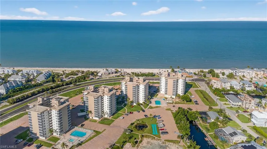 Aerial view of property and surrounding area with waterfront with a beach