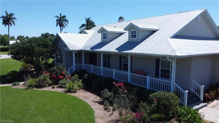 View of front of home featuring covered porch, a chimney, and a front lawn