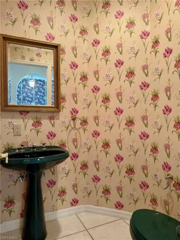 Half bath with wallpapered walls, baseboards, and tile patterned flooring