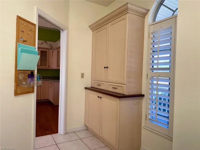 Hallway with light tile patterned floors, baseboards, and a wealth of natural light