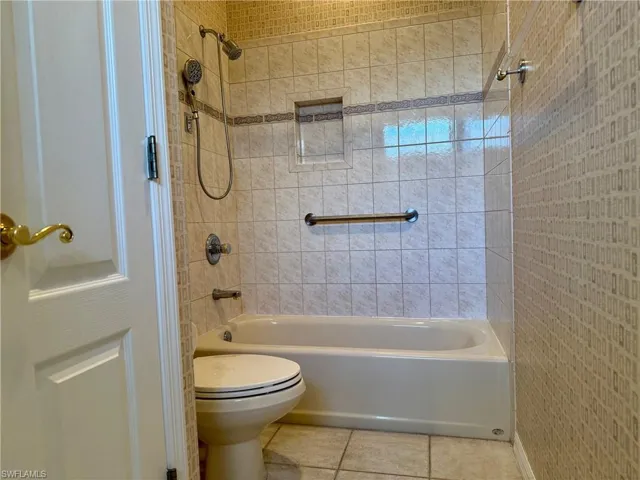 Full bath with tile patterned floors, toilet, and shower / tub combination