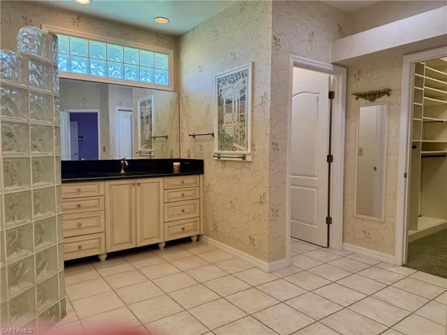 Bathroom with baseboards, vanity, tile patterned flooring, and wallpapered walls