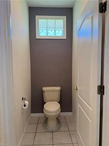 Bathroom with tile patterned floors, toilet, and baseboards