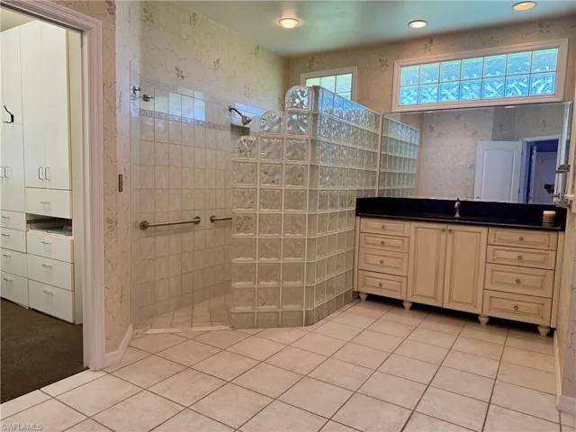 Bathroom with vanity, a walk in shower, tile patterned flooring, and wallpapered walls
