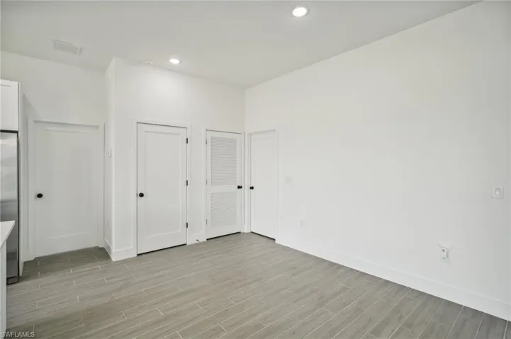 Unfurnished bedroom featuring light hardwood / wood-style floors, stainless steel fridge, and multiple closets