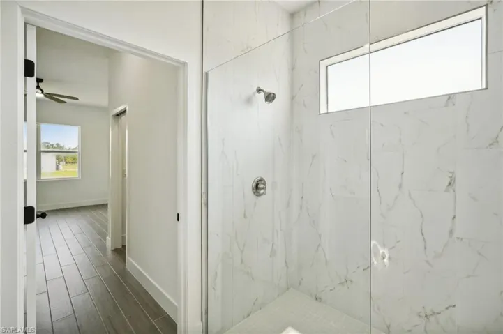 Bathroom with a tile shower, hardwood / wood-style floors, and ceiling fan
