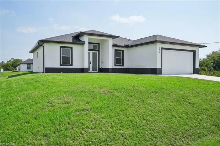 View of front of property featuring a garage and a front lawn