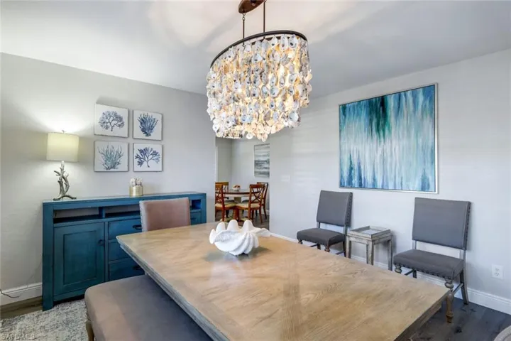 Dining room with a oyster chandelier, large window, and French door to pool/lanai/grill