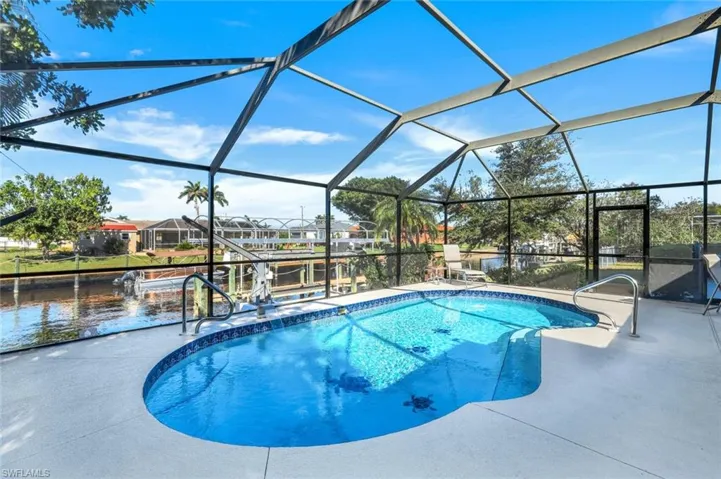 View of swimming pool with a lanai, a patio, and a water view