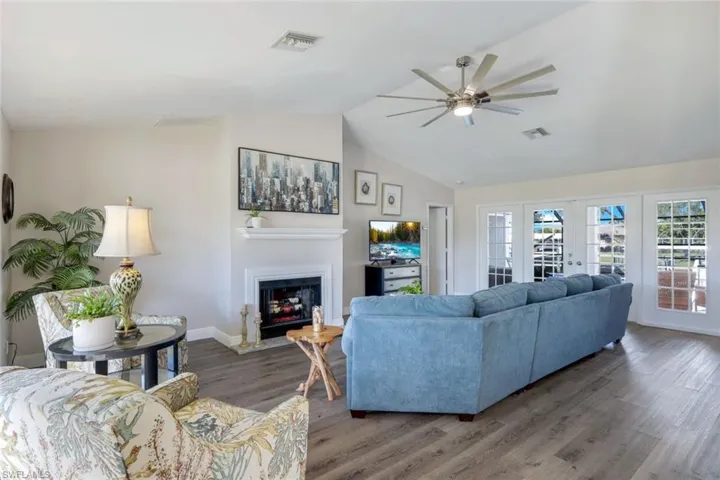 Living room featuring abundance of natural light, ceiling fan, lofted ceiling, and french doors