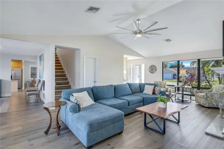 Living room featuring ceiling fan, light hardwood / wood-style floors, a wealth of natural light, and vaulted ceiling