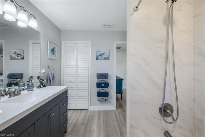 Bathroom featuring 2 sink vanity, walk in closet , and separated toilet and tiled shower