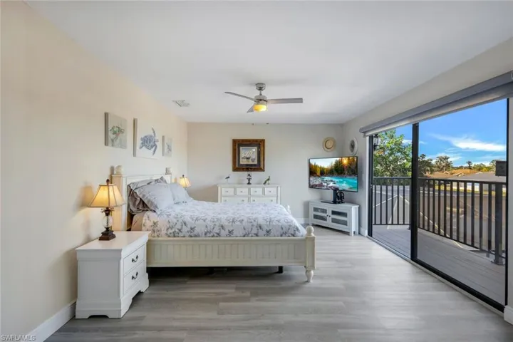 Bedroom with access to private balcony, ceiling fan, and slider to serene water views