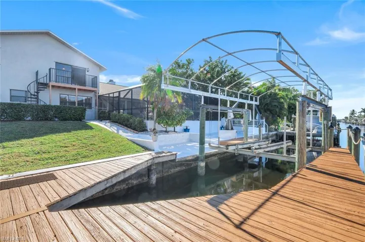 View of dock featuring a water view, a yard, and a balcony