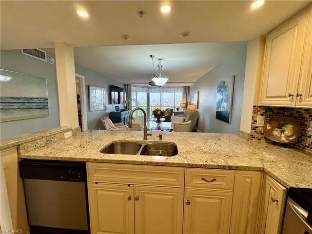 Kitchen featuring sink, stainless steel dishwasher, light stone counters, and kitchen peninsula