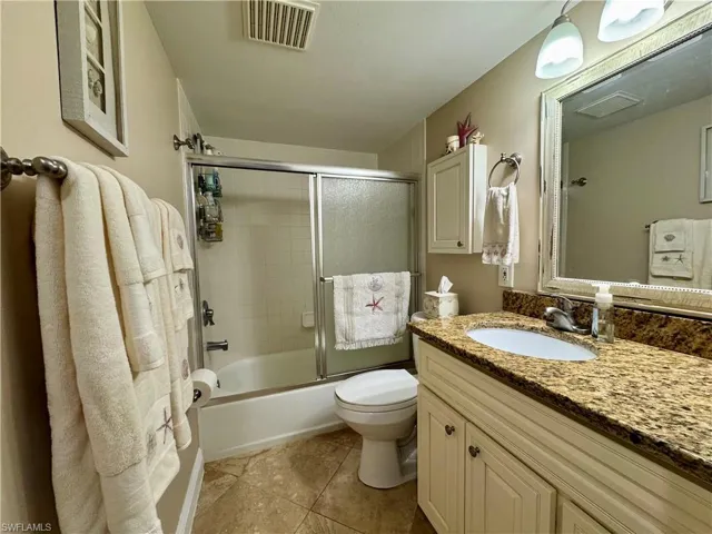 Full bathroom with enclosed tub / shower combo, tile patterned flooring, vanity, and toilet