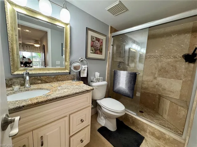 Bathroom with toilet, vanity, tile patterned flooring, and a shower with shower door