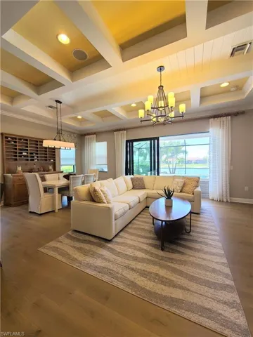 Living room featuring beam ceiling, coffered ceiling, hardwood / wood-style floors, and an inviting chandelier