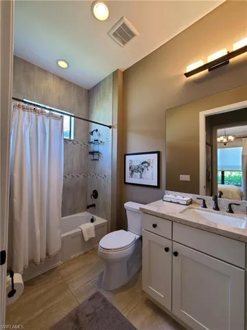Full bathroom featuring shower / tub combo with curtain, vanity, tile patterned flooring, an inviting chandelier, and toilet