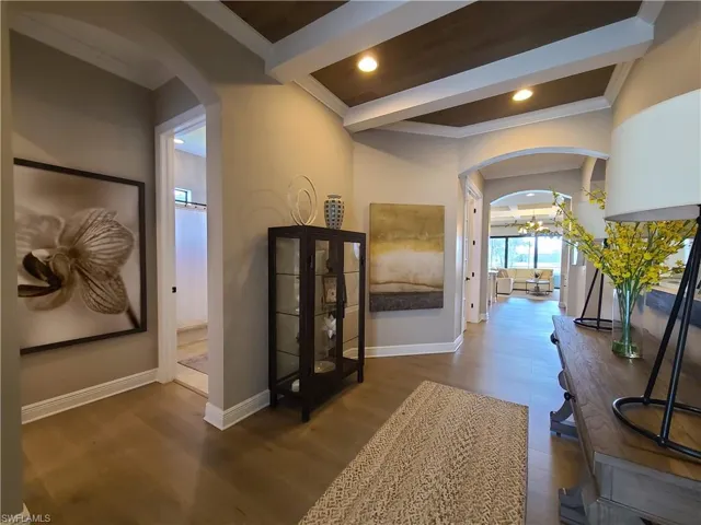 Hall featuring ornamental molding, beamed ceiling, a chandelier, and dark wood-type flooring