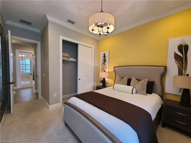 Bedroom with light colored carpet, an inviting chandelier, a closet, and ornamental molding