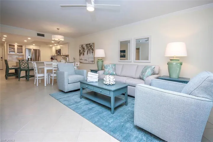 Living area featuring crown molding, light tile patterned flooring, and a ceiling fan