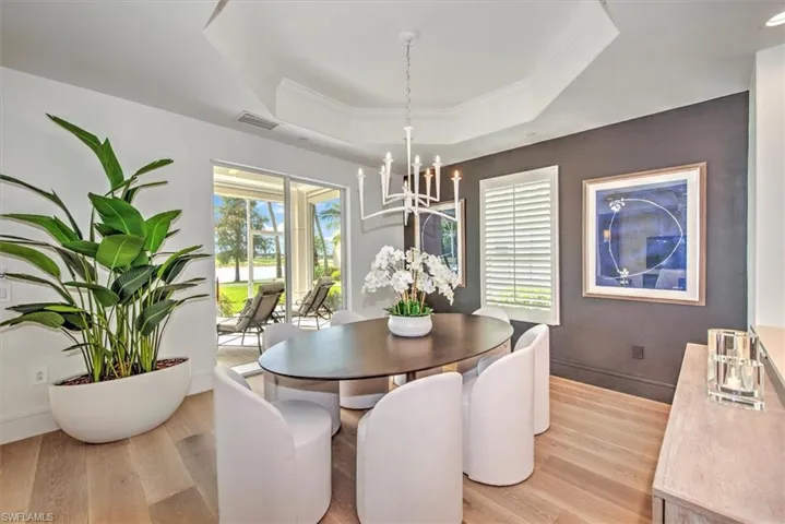 Dining area featuring a chandelier, light hardwood / wood-style floors, and a raised ceiling